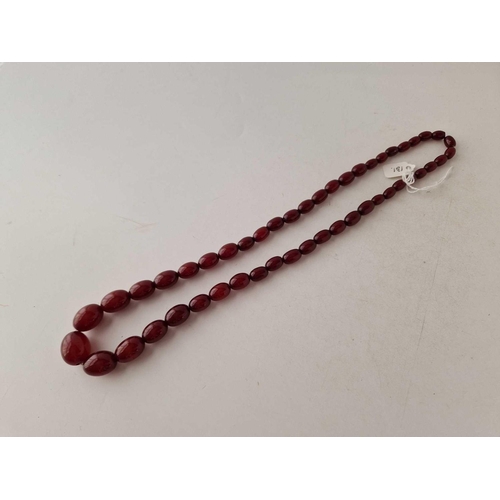 131 - A STRING OF CHERRY AMBER BEADS 26 INCH 64.6 GMS