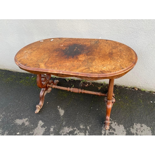 1711 - An oval Victorian figured Walnut writing table in tressel shape base with scroll feet 45