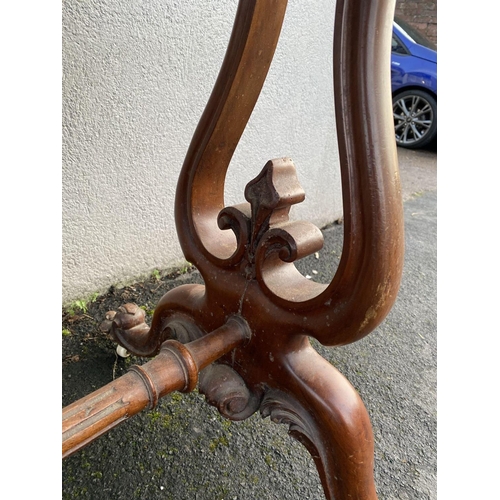 1711 - An oval Victorian figured Walnut writing table in tressel shape base with scroll feet 45