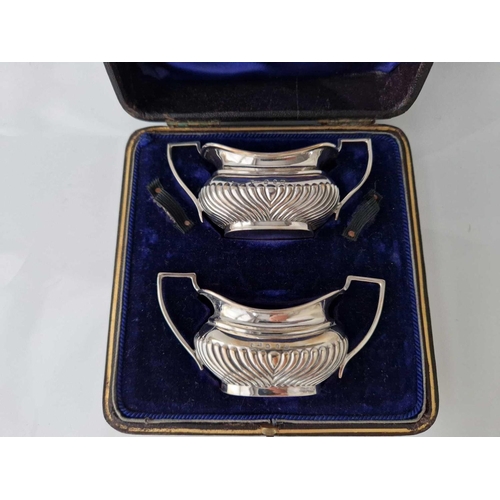 1022 - A boxed pair of half fluted salts with scroll handles, 4