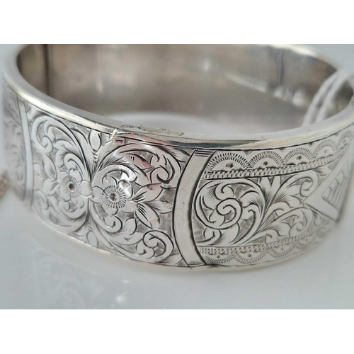 340 - A 20mm wide floral engraved silver bangle