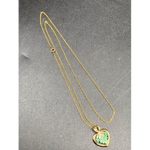 515 - A emerald heart pendant designed as a bouquet of emeralds framed by the gold heart on a gold chain 1... 