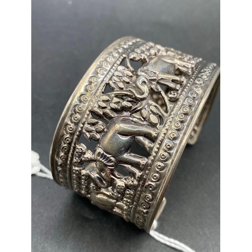 174 - A wide silver cuff bangle embossed with elephants