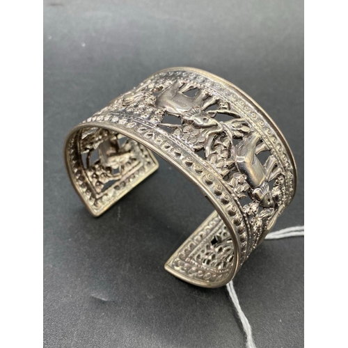 174 - A wide silver cuff bangle embossed with elephants