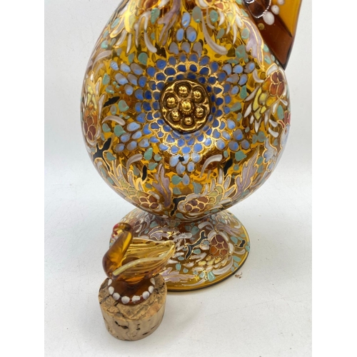 1611 - A decorative amber glass claret jug and stopper enamelled with flowers 12 inches high