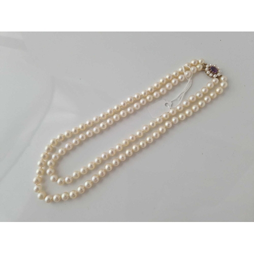 354 - A DOUBLE STRAND UNGRADUATED CULTURED PEARLS WITH 9CT AMETHYST AND PEARL CLASP 15 INCH BOXED