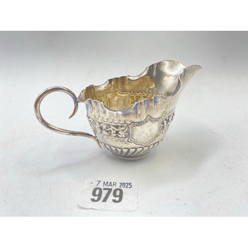 979 - A small embossed cream jug with scroll handle, 4.5 inches wide, London 1891 by G & J, 57 g.