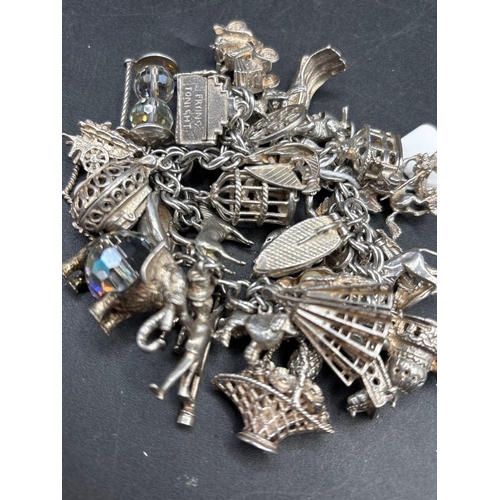 111 - An exceptional very heavy silver charm bracelet with over 30 charms 133 g.