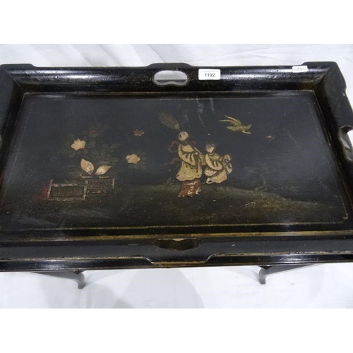 1192 - Lacquered tray-top table, the black ground with figural decoration, on stand with X-shaped stretcher