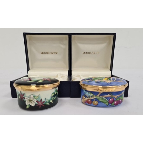 148 - Moorcroft enamel patch box, oval and decorated with cherries on a blue ground, 6cm wide, boxed and a... 