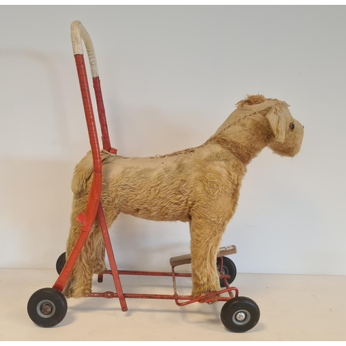 550 - Push-a-long straw-stuffed dog on wheels, 49cm high, worn