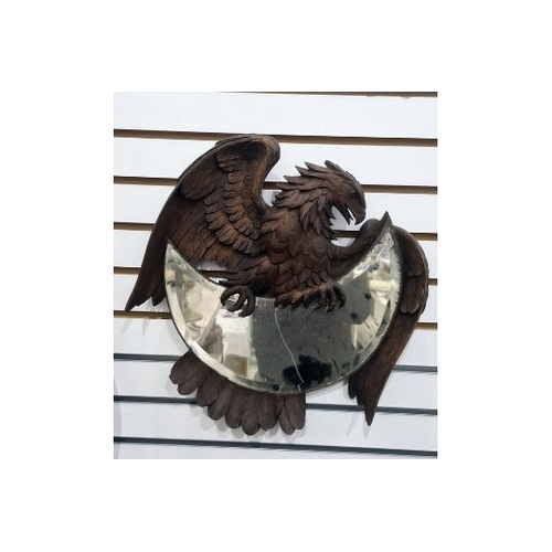 183 - Early 20th century Black Forest mirror modelled as a carved eagle holding a crescent-shaped bevelled... 