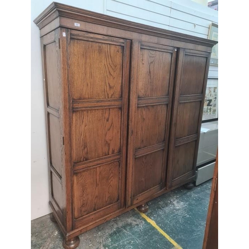 1029 - 20th century oak three-door wardrobe with cavetto moulded cornice above the panelled doors, with flu... 