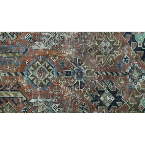 1318 - Red ground rug, possibly Persian, and possibly circa 1860, with allover hooked arabesques and medall... 