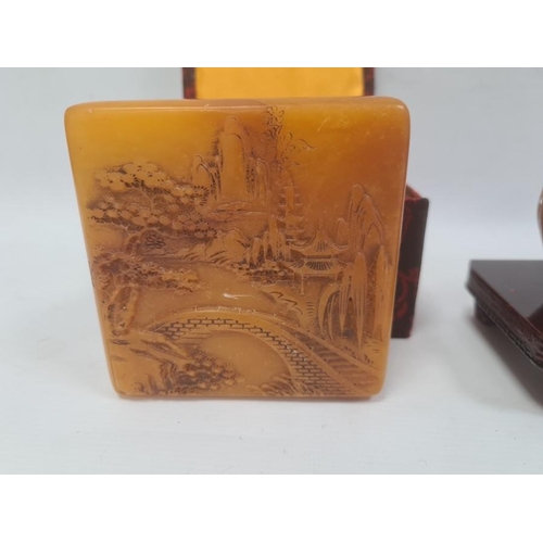 168 - Simulated soapstone resin carving of wooded scene and the hardwood stand, 23cm side and a variegated... 