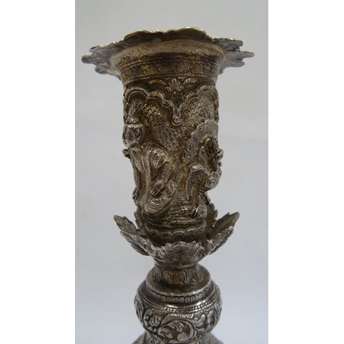 486 - A pair of Indian/Burmese white coloured metal candlesticks, relief of warriors/hunters and animals, ... 