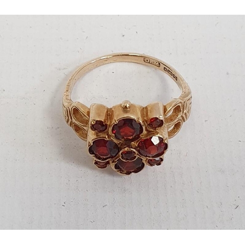 565 - 9ct gold lady's ring with four large and five small garnets, in flowerhead setting, 4.5g