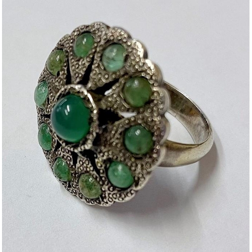 616 - A silver coloured metal and emerald ring, possible Indian, circular/flower shaped with central caboc... 