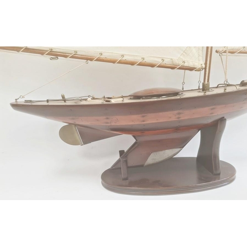 152 - Varnished wood model yacht with canvas sails and metal fittings and the associated wooden stand, 91c... 