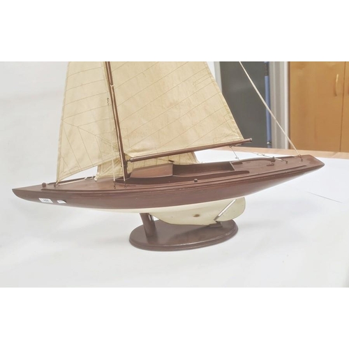 153 - Varnished and painted wood model yacht with canvas sails and the associated wooden stand, 102cm high... 