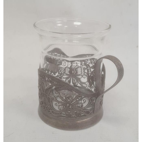 396 - Silver-coloured metal filigree cup holder, flower decorated, with marks to base and a glass cup (not... 