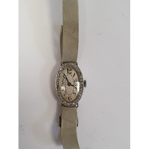 607 - A 1920s platinum and diamond lady's wristwatch on fabric strap, oval with Arabic numerals and an ova... 