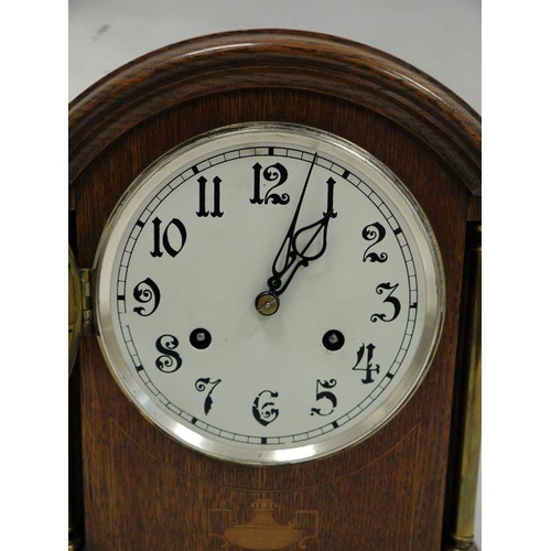 1057 - Oak-cased mantel clock with arched top, Arabic numerals to the dial, on plinth base