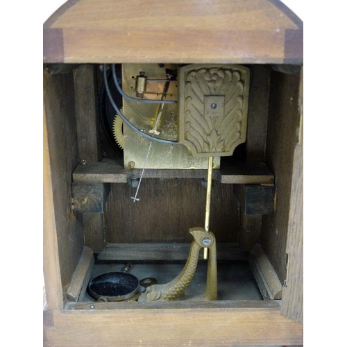 1057 - Oak-cased mantel clock with arched top, Arabic numerals to the dial, on plinth base