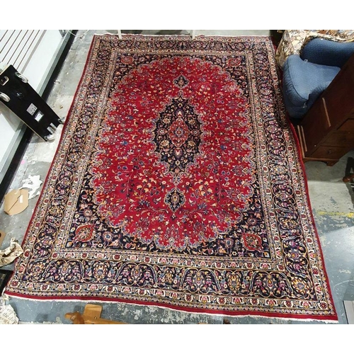 1094 - Eastern-style rug with central medallion on a red ground foliate decorated field, navy ground spandr... 