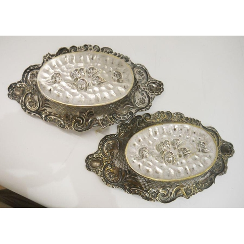 296 - Pair of silver-plated sweetmeat dishes with pierced decoration, cherubs on the base (copper showing ... 