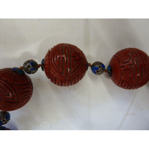 363 - Oriental cinnabar and enamel shou necklace, the large cinnabar beads carved geometric design and flo... 