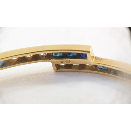 523 - 18ct gold, sapphire and diamond bangle, fine crossover pattern and set with 14 square-cut sapphires ... 