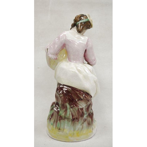 14 - Staffordshire pottery figure of a lady vintner, late 19th century, she modelled seated holding a bas... 