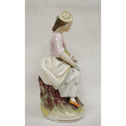 14 - Staffordshire pottery figure of a lady vintner, late 19th century, she modelled seated holding a bas... 