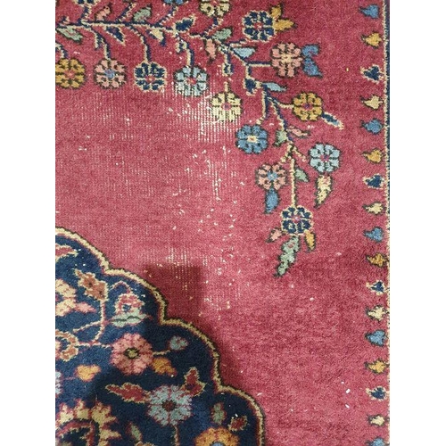 1038 - Persian-style carpet having shaped oval floral central medallion to the maroon ground, cream spandre... 