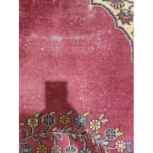 1038 - Persian-style carpet having shaped oval floral central medallion to the maroon ground, cream spandre... 