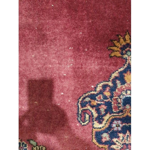 1038 - Persian-style carpet having shaped oval floral central medallion to the maroon ground, cream spandre... 