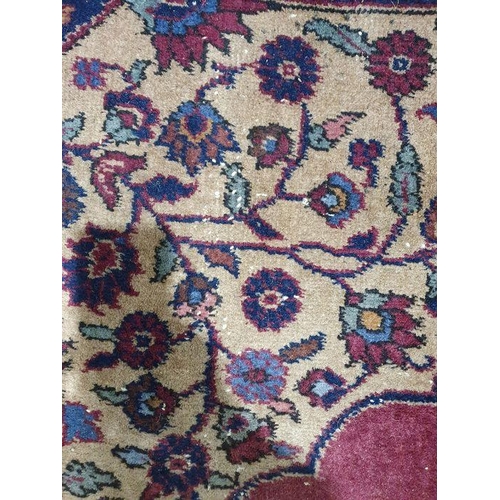 1038 - Persian-style carpet having shaped oval floral central medallion to the maroon ground, cream spandre... 