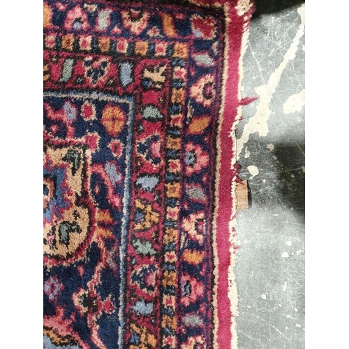 1038 - Persian-style carpet having shaped oval floral central medallion to the maroon ground, cream spandre... 