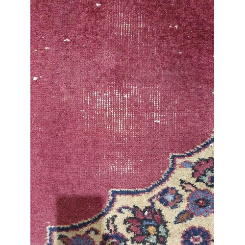 1038 - Persian-style carpet having shaped oval floral central medallion to the maroon ground, cream spandre... 