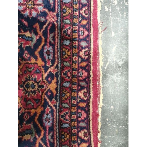 1038 - Persian-style carpet having shaped oval floral central medallion to the maroon ground, cream spandre... 