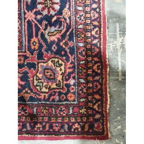 1038 - Persian-style carpet having shaped oval floral central medallion to the maroon ground, cream spandre... 