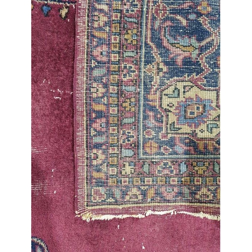 1038 - Persian-style carpet having shaped oval floral central medallion to the maroon ground, cream spandre... 