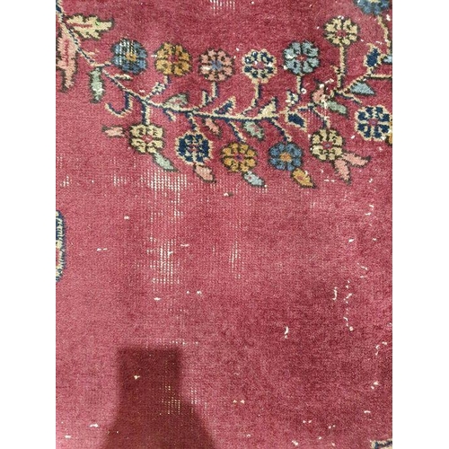 1038 - Persian-style carpet having shaped oval floral central medallion to the maroon ground, cream spandre... 