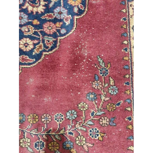 1038 - Persian-style carpet having shaped oval floral central medallion to the maroon ground, cream spandre... 