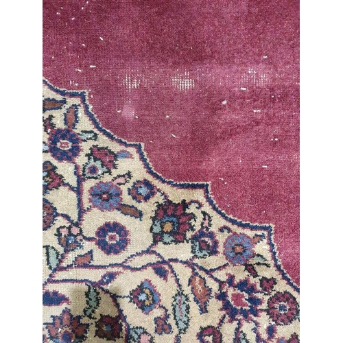 1038 - Persian-style carpet having shaped oval floral central medallion to the maroon ground, cream spandre... 