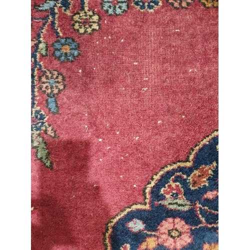 1038 - Persian-style carpet having shaped oval floral central medallion to the maroon ground, cream spandre... 