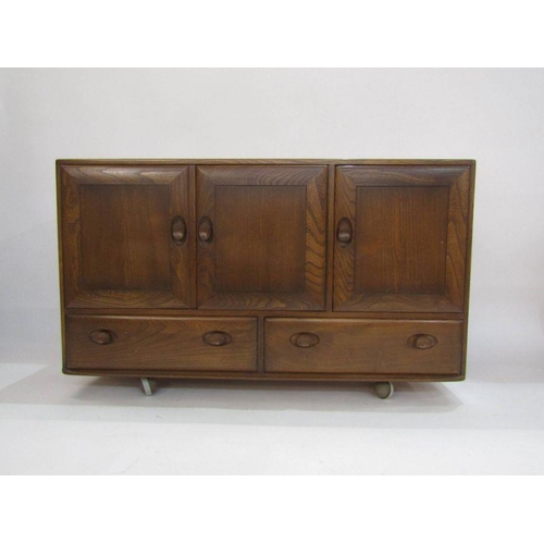 1059 - Ercol elm sideboard with oval dished handles, 3 cupboard doors above 2 drawers on castors, 75.5cm hi... 