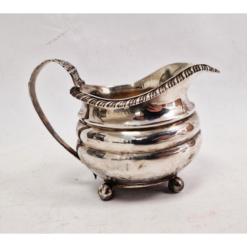 391 - Georgian silver milk jug, the handle embossed with fruits and vine, ribbed body, ball feet, London d... 