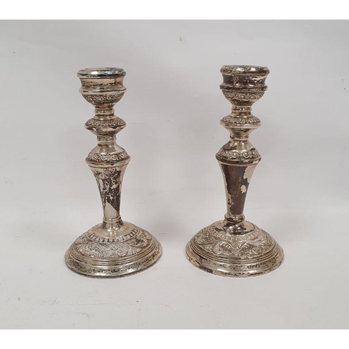 313 - Pair of 1920's silver weighted candlesticks, relief decorated on a circular base, Birmingham 1924, m... 